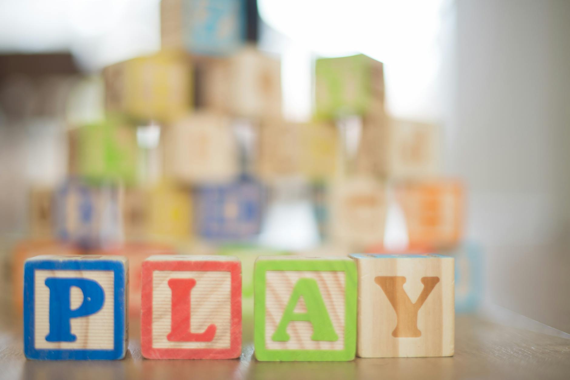 depth of field photography of p l a y wooden letter decors on top of beige wooden surface